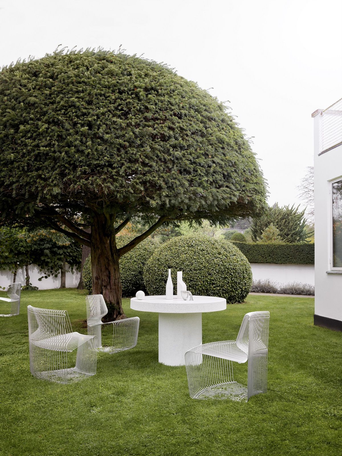 Pantonova System Drahtstühle im Garten mit Tisch. Design Sitzmöbel für stilvolles Wohnen im Freien.