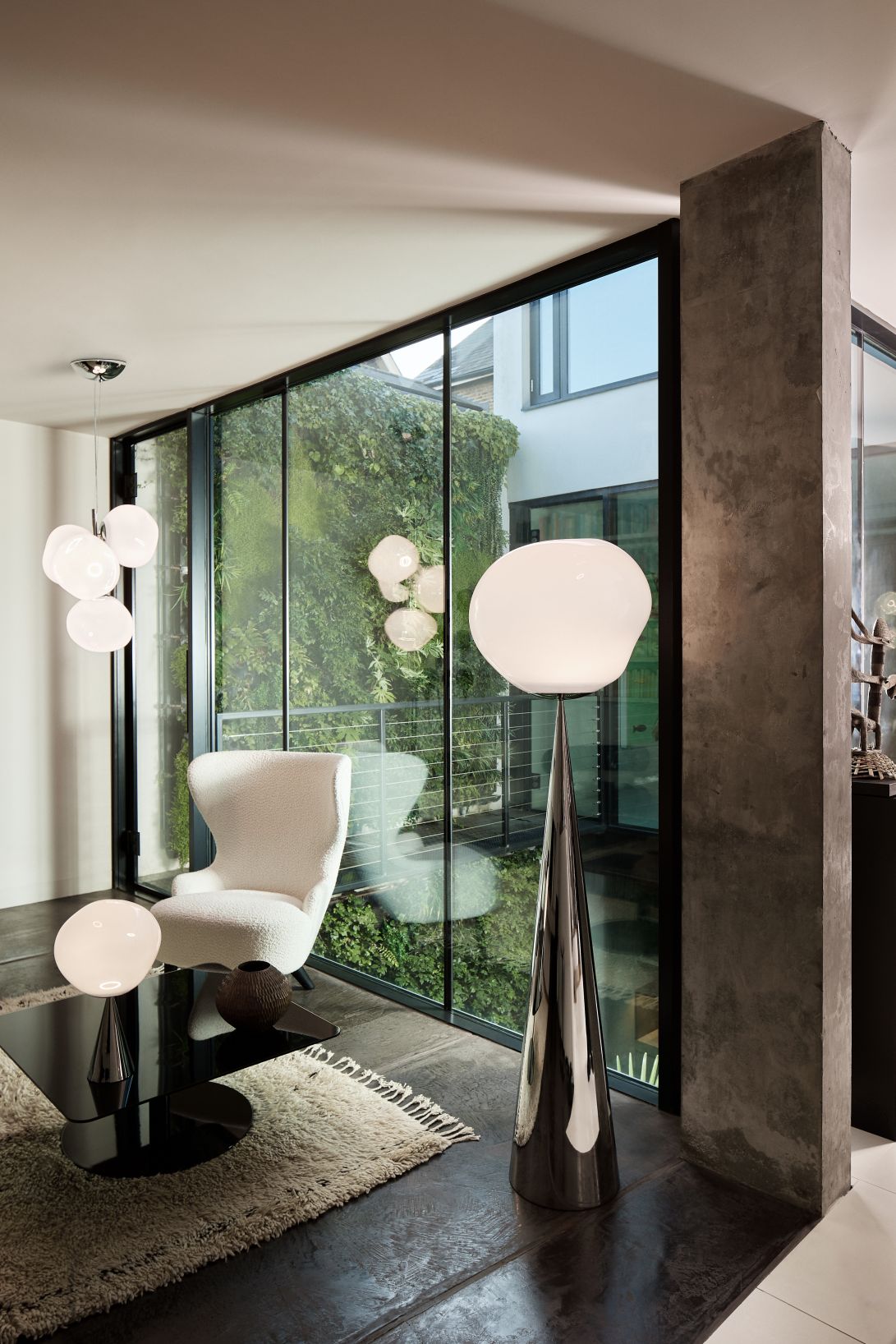 Silberne Tom Dixon Melt Cone Fat Tischleuchte im modernen Wohnzimmer mit großem Fenster.