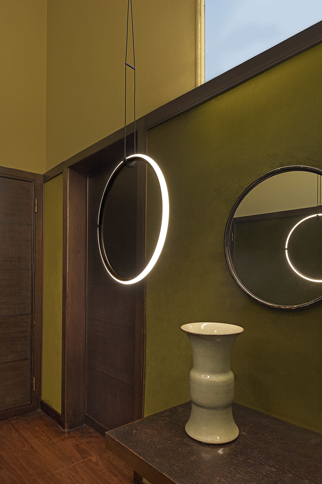 Pendelleuchte als Ring mit LED-Licht, Flos Rosette, hängt über einem Tisch.