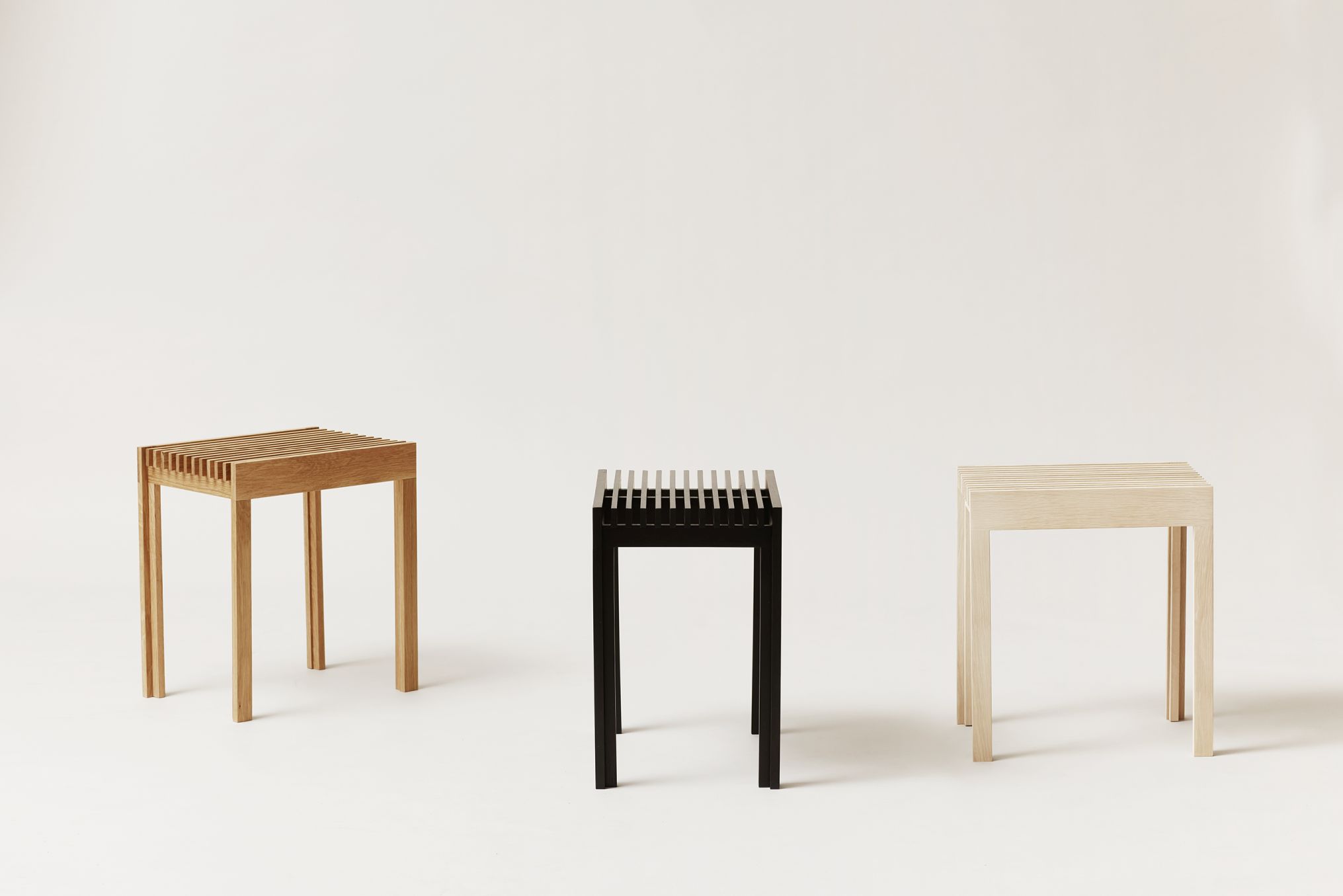 Drei Form & Refine Lightweight Hocker aus Eiche, natur, schwarz gebeizt und hell, auf weißem Grund.