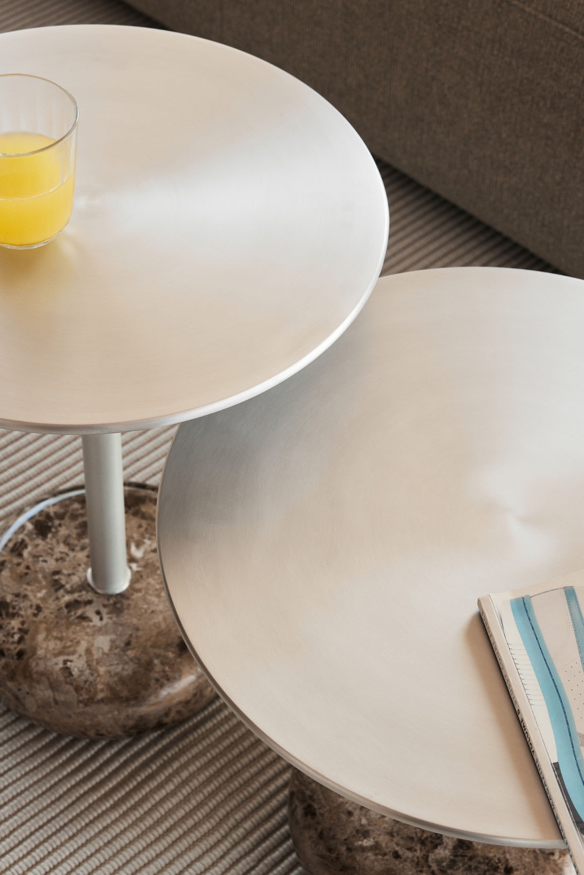 Nahaufnahme von zwei runden Northern Ton Beistelltischen H50cm mit Marmorfuß, einer mit Orangensaft.