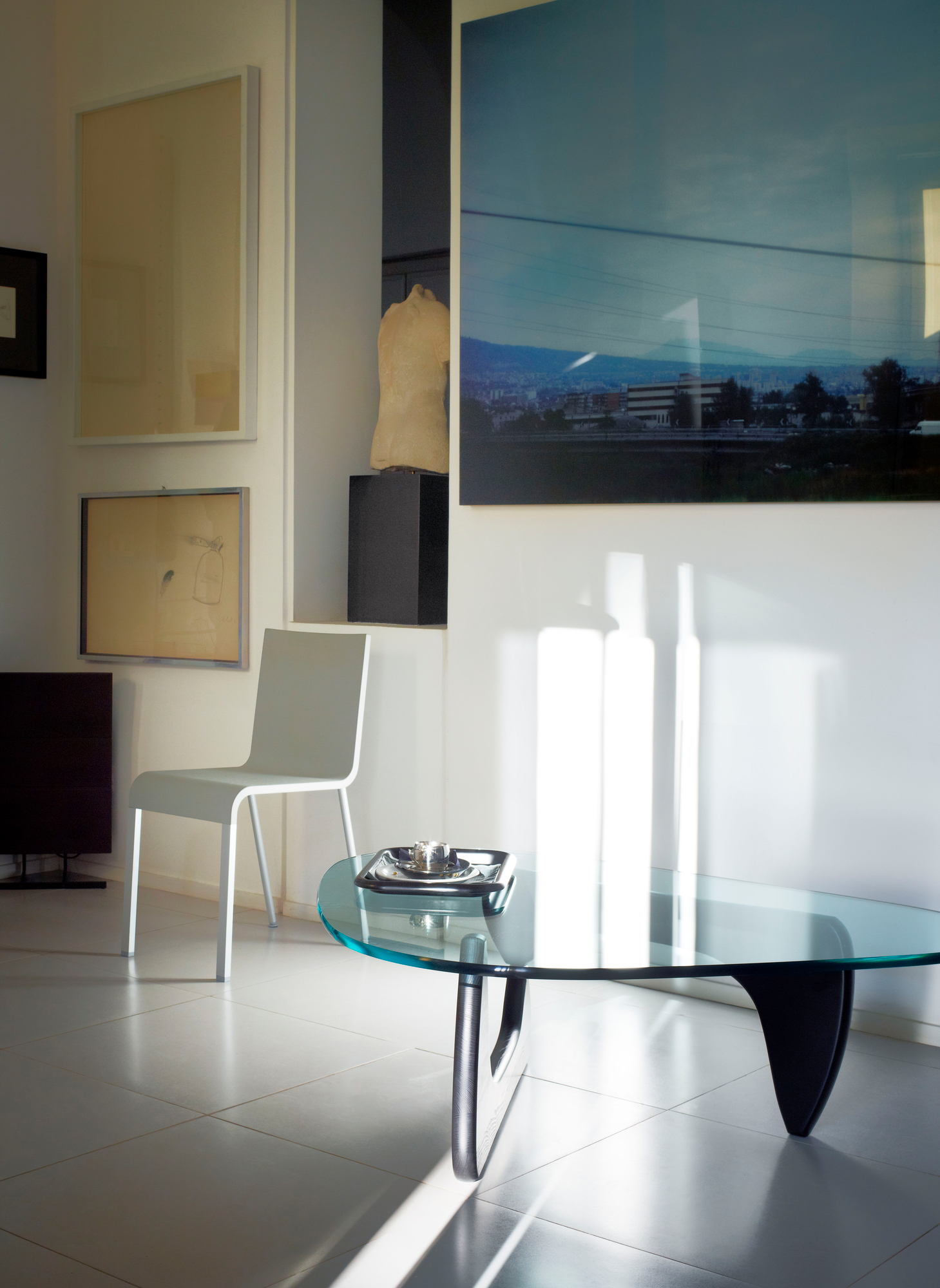 Noguchi Couchtisch mit Glasplatte und Nussbaum-Gestell von Vitra in modernem Wohnraum.