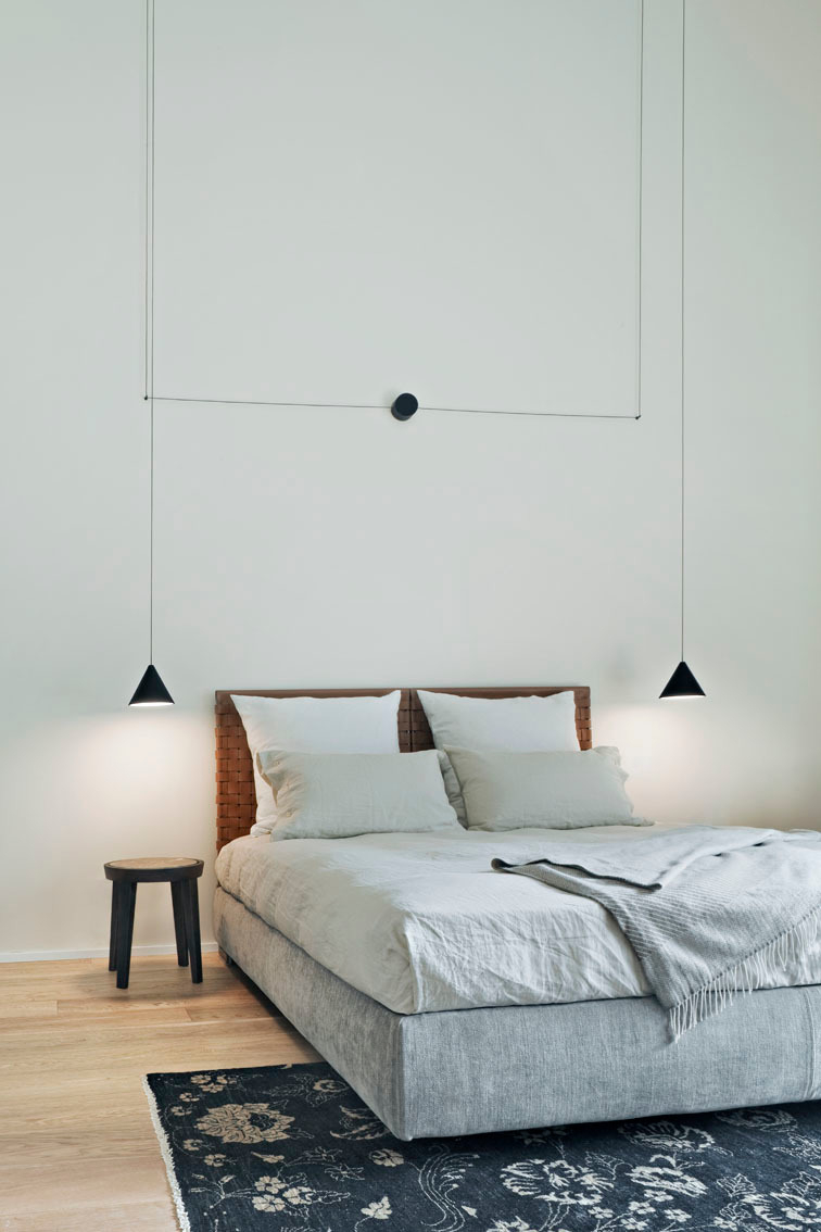 Schlafzimmer mit Flos String Light Pendelleuchten und Wandrosette für moderne Beleuchtung.
