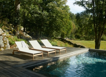 Drei helle Pelagus Sonnenliegen von Skagerak auf Holzdeck neben einem Pool im Garten.