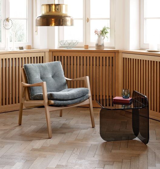 ClassiCon Sol Beistelltisch aus Parsolglas bronze neben Sessel in modernem Wohnraum.