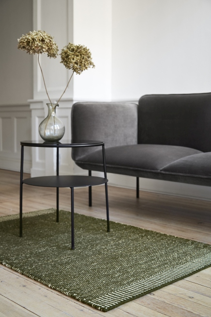 Rombo Rug Teppich in Weiß/Grau, 90x140 cm, vor Sofa und Tisch im Wohnzimmer.