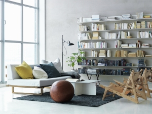 Helles Wohnzimmer mit String Regal an der Wand, Sofa und modernem Design.