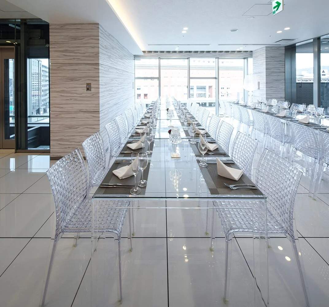 Langer Tisch mit vielen transparenten Ami Ami Stühlen von Kartell für eine Veranstaltung.