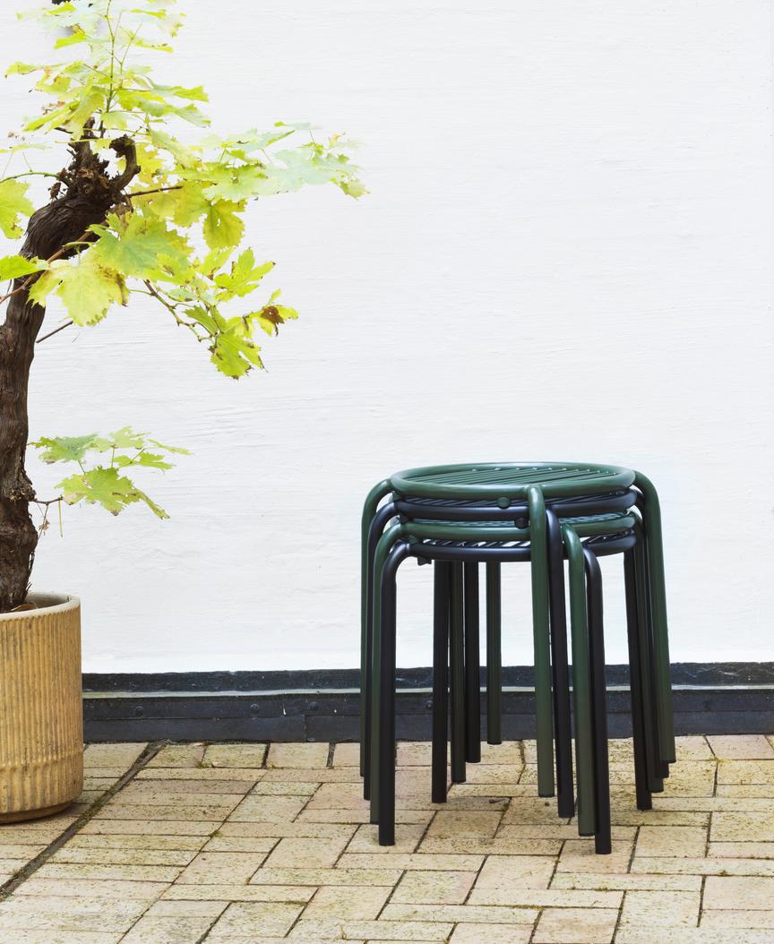 Stapel von grünen Vig Stool Hockern von Normann Copenhagen für den Außenbereich auf Pflastersteinen.