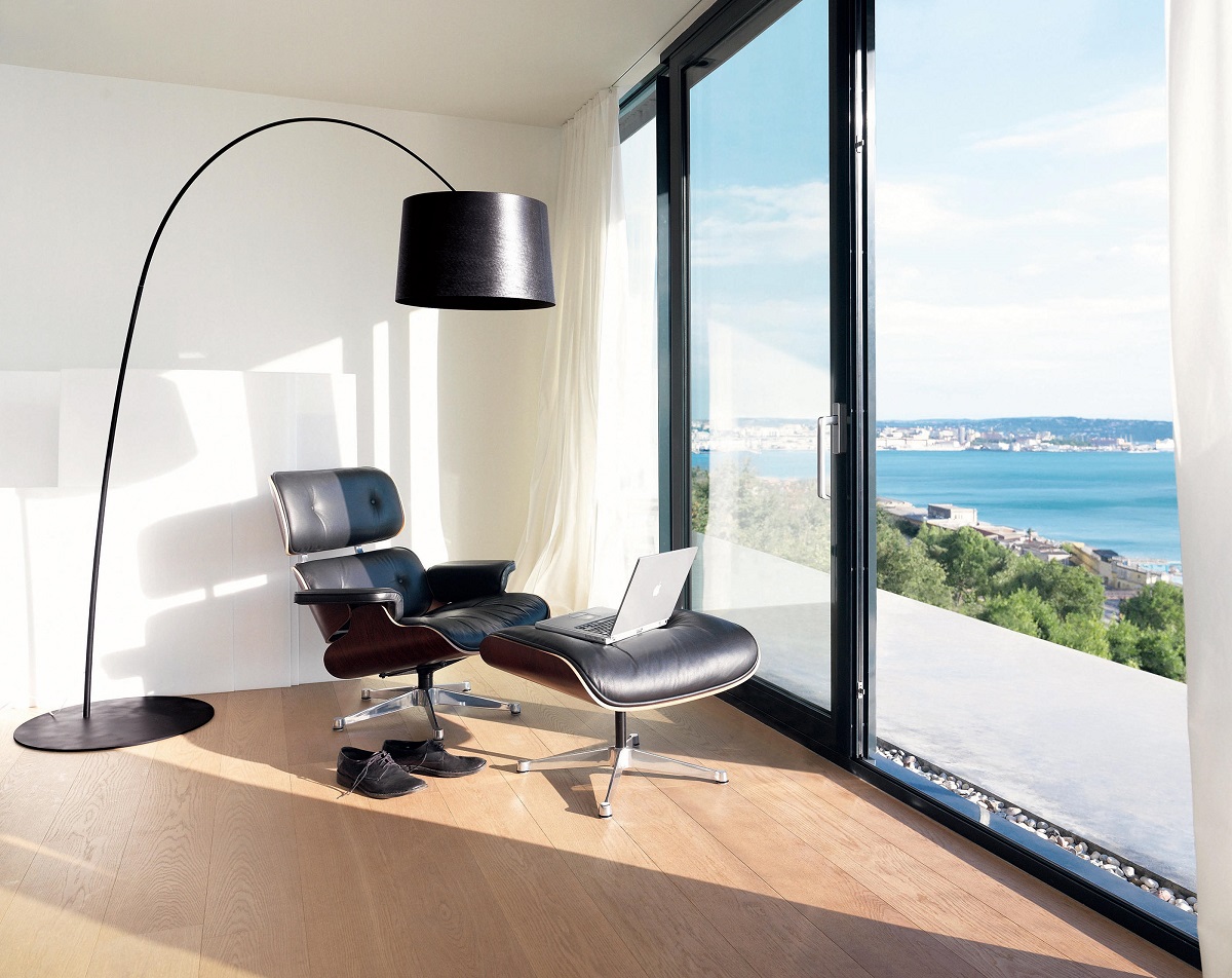 Moderne Twiggy Stehleuchte von Foscarini in Grau-Beige neben Sessel mit Meerblick im hellen Wohnzimmer.