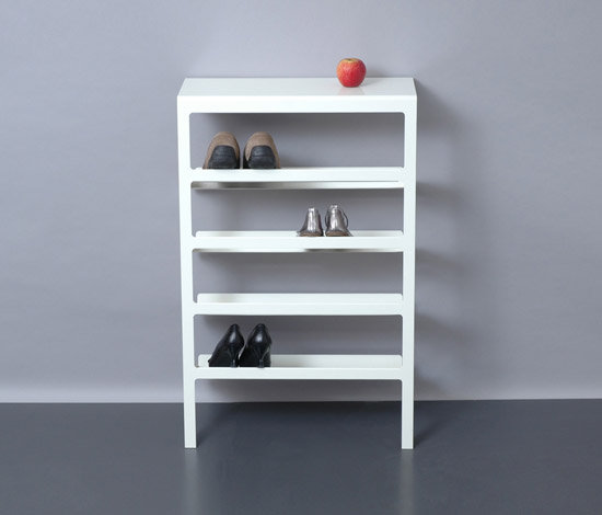 Weißes Mila Schuhregal Mox mit vier Ablagen, darauf Schuhe und ein Apfel.