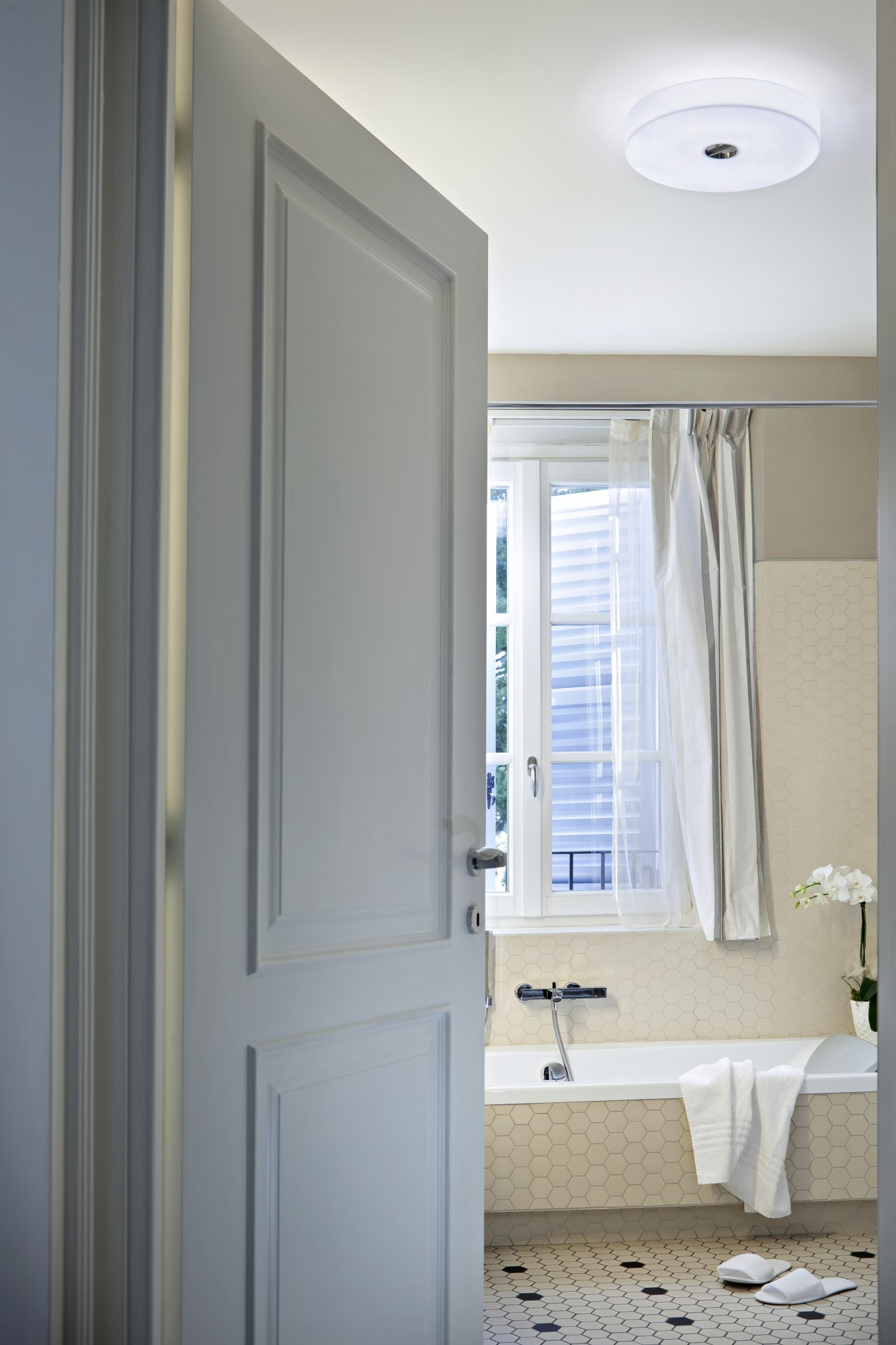 Badezimmer mit Flos Button Deckenleuchte: Moderne Deckenlampe sorgt für helles Licht im Raum.