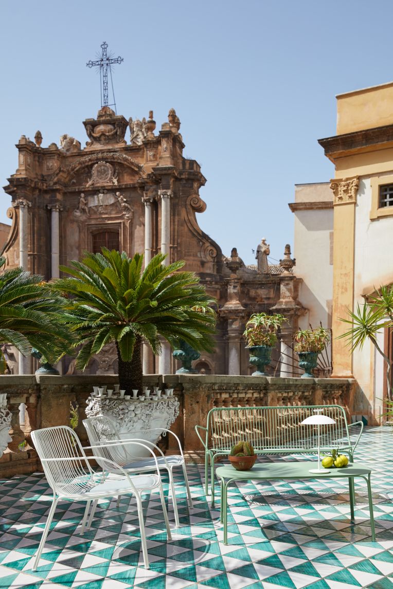 Hiray Outdoor Kaffeetisch von Kartell auf einer Terrasse mit Stühlen und Bank.