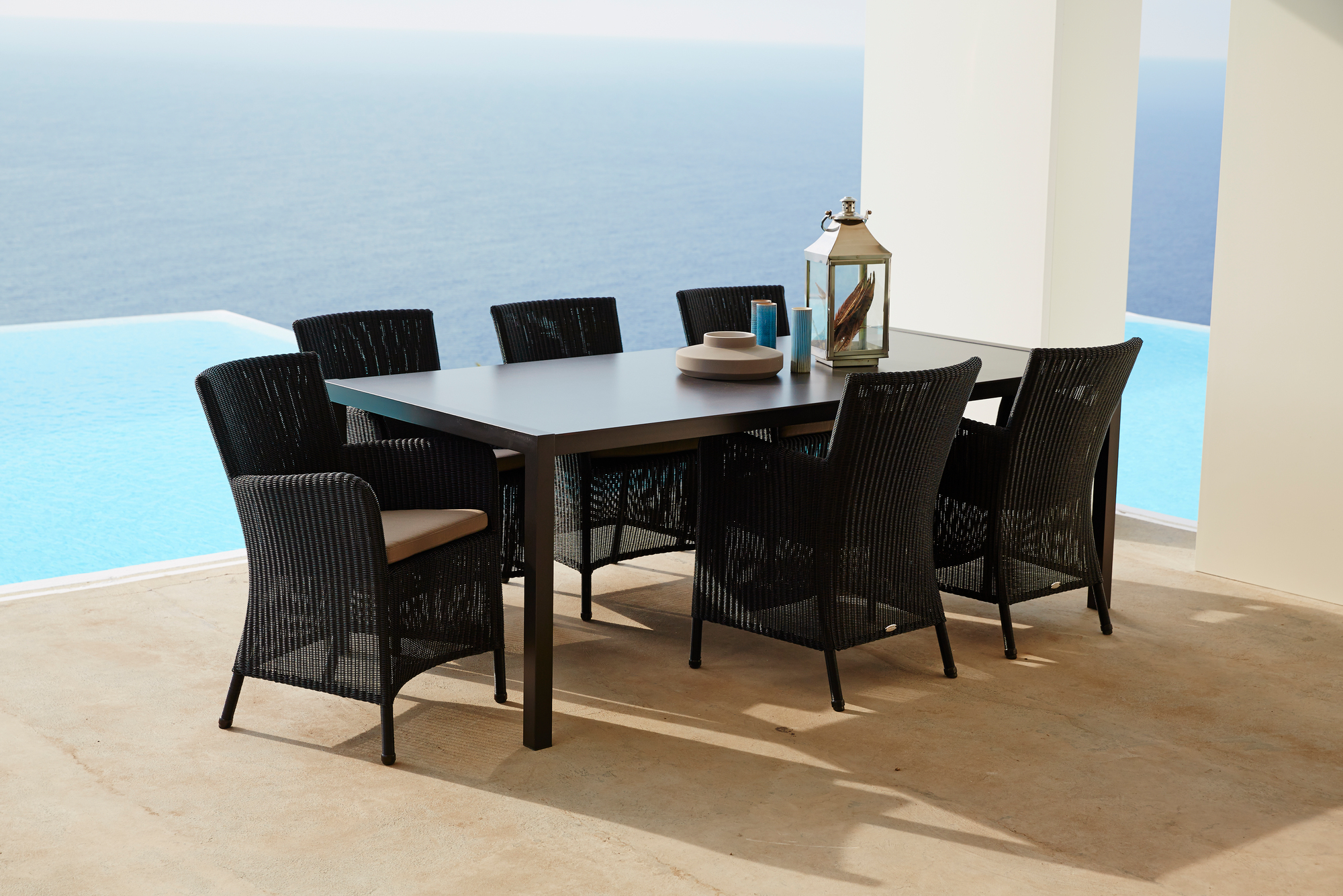 Schwarzer Cane-Line Outdoor Sessel Hampsted aus Rattan mit Tisch und Meerblick. Gartenmöbel für Terrasse.