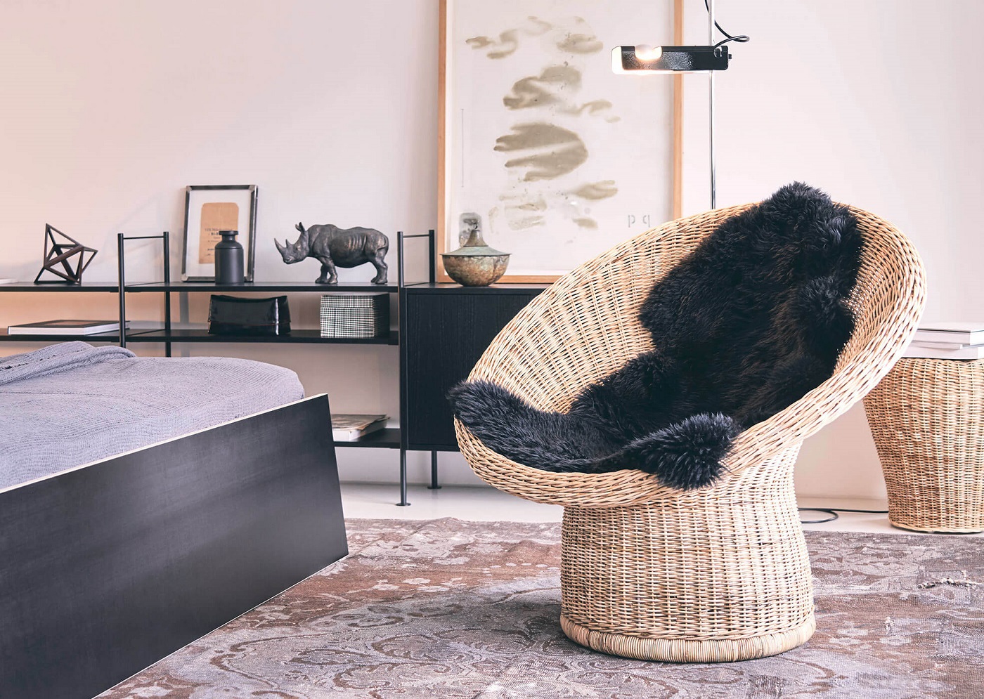 E10 Rattansessel von Richard Lampert mit schwarzem Schaffell in modernem Schlafzimmer. Rattanmöbel für stilvolles Wohnen.