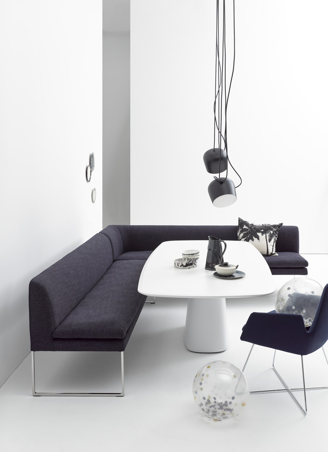 Elegante, dunkelgraue Mell Polsterbank von Cor mit Metallgestell und weißem Esstisch in modernem Interieur.