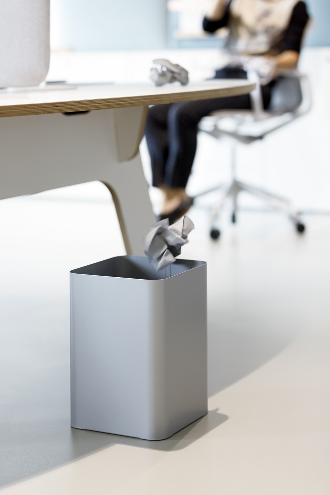 Grauer Cascando Flow II Papierkorb im Büro, Papier wird hineingeworfen. Moderner Abfalleimer für Büromöbel.