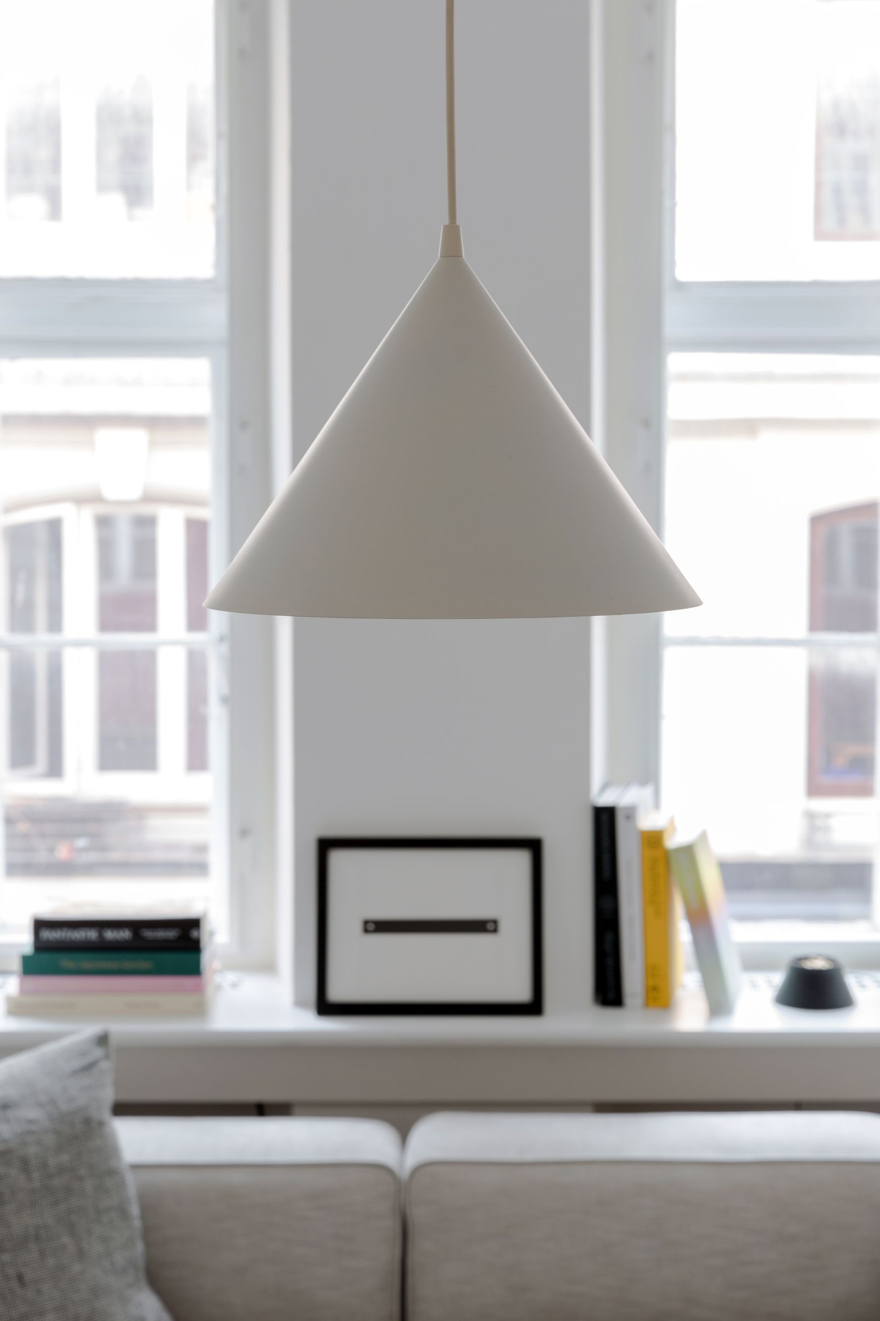 Weiße Annular Pendelleuchte von Woud vor einem Fenster, minimalistisches Design, moderne Beleuchtung.