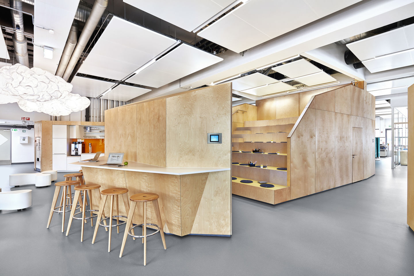 Tabouret Haut Barhocker aus Eiche natur vor einer Theke in einem modernen Büro.