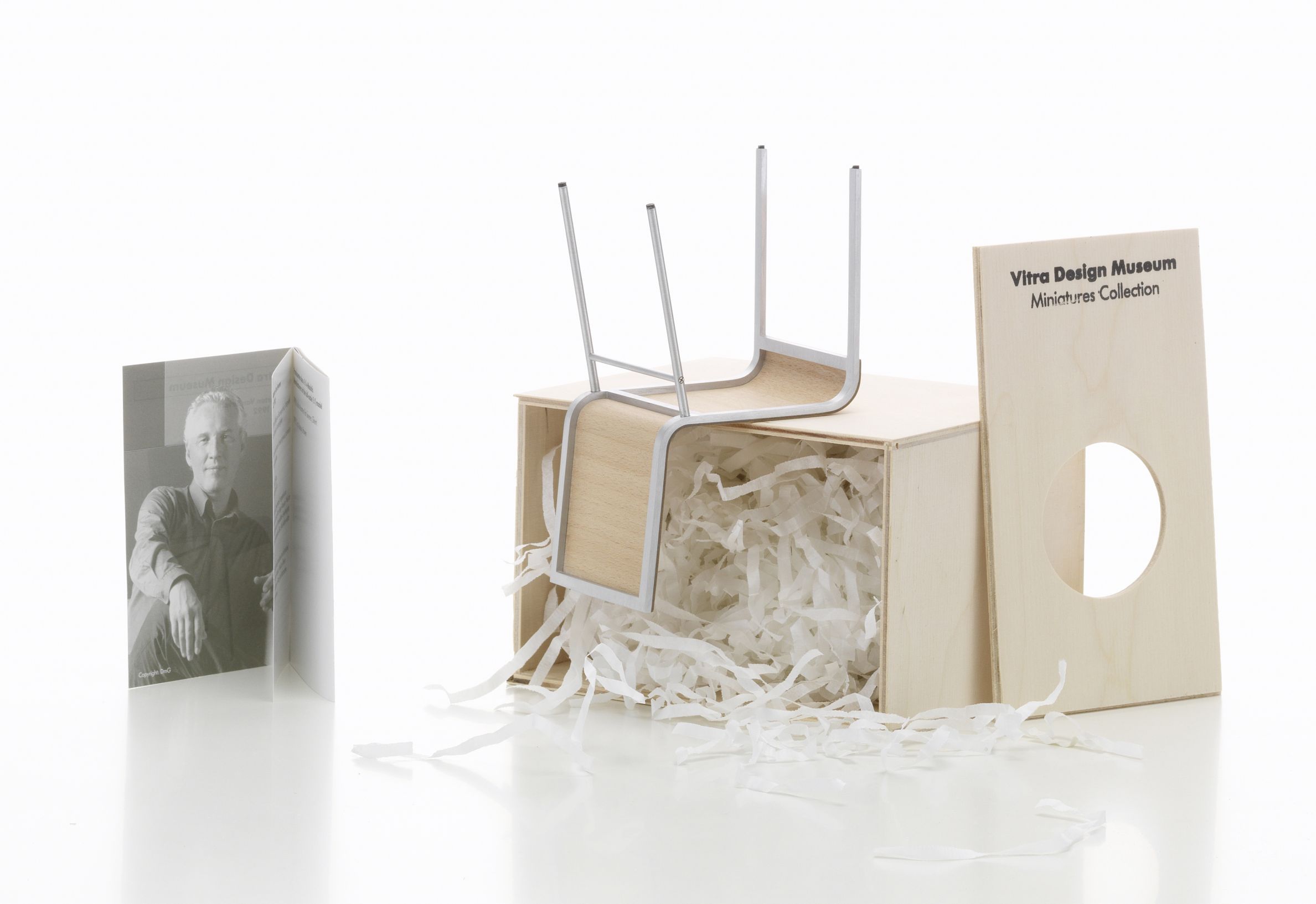 .02 Stuhl Miniatur von Vitra, liegend auf einer Holzkiste mit Papierwolle.