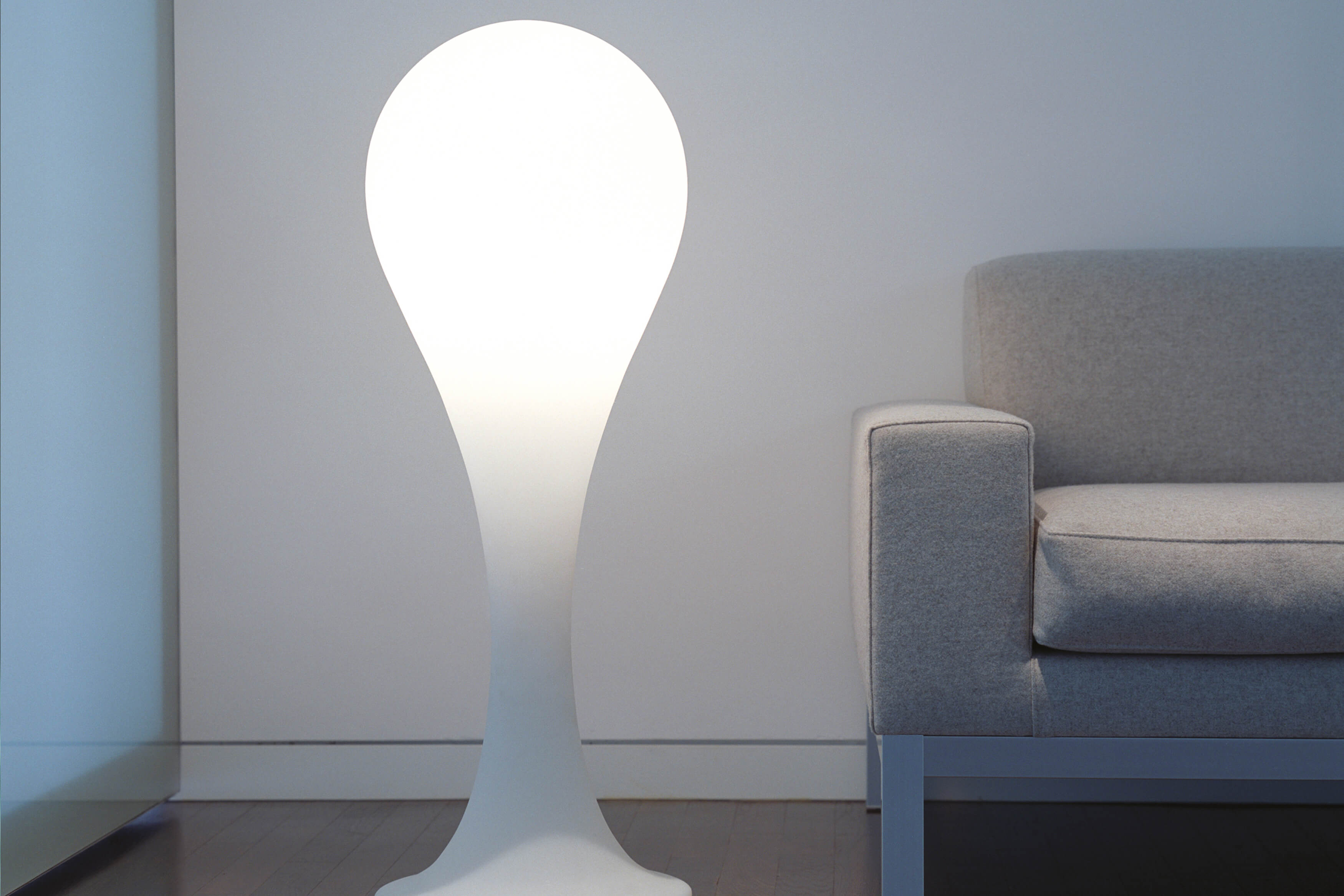 Helle Liquid Light Drop Standleuchte von Next neben einem grauen Sofa im modernen Wohnzimmer.