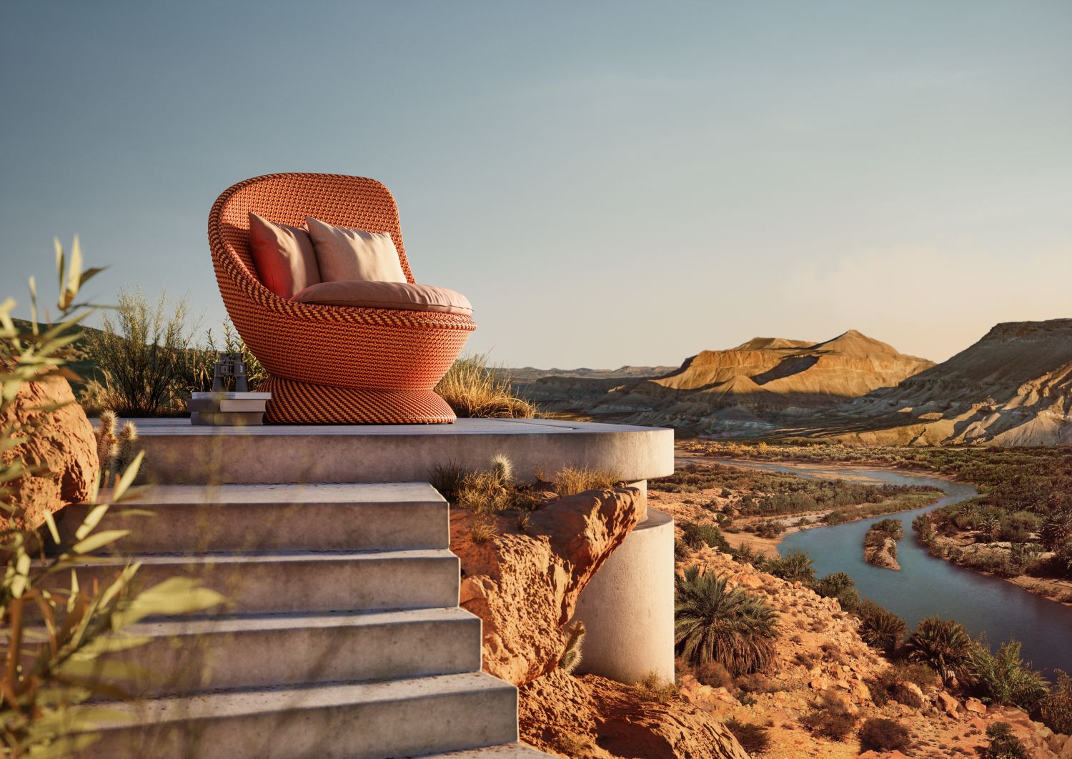 Papyon Hochlehner mit Kissen von Dedon, orangefarbener Outdoor Sessel auf Terrasse mit Flussblick.