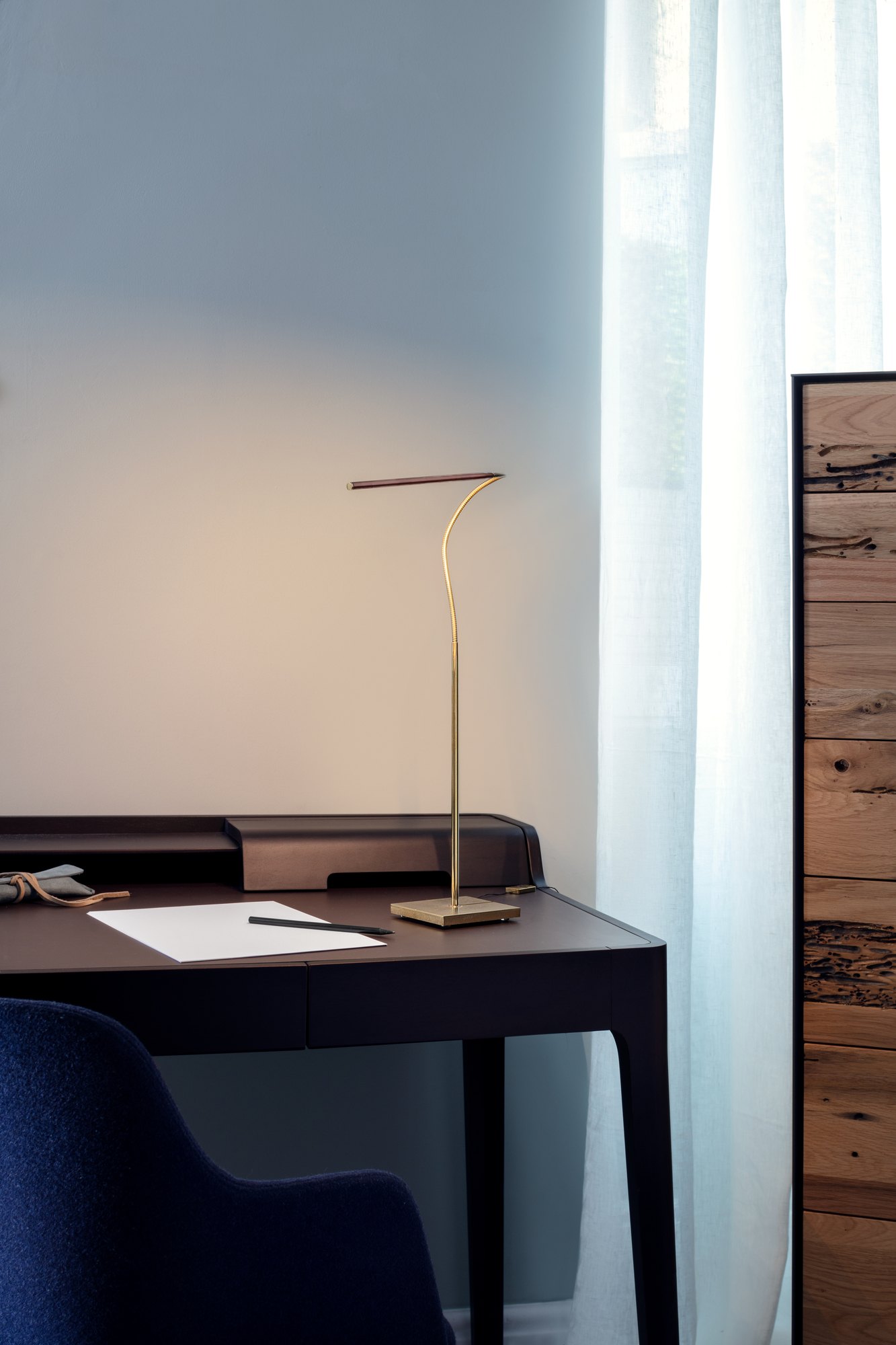 Lola T LED Tischleuchte von Catellani & Smith auf einem dunklen Schreibtisch.