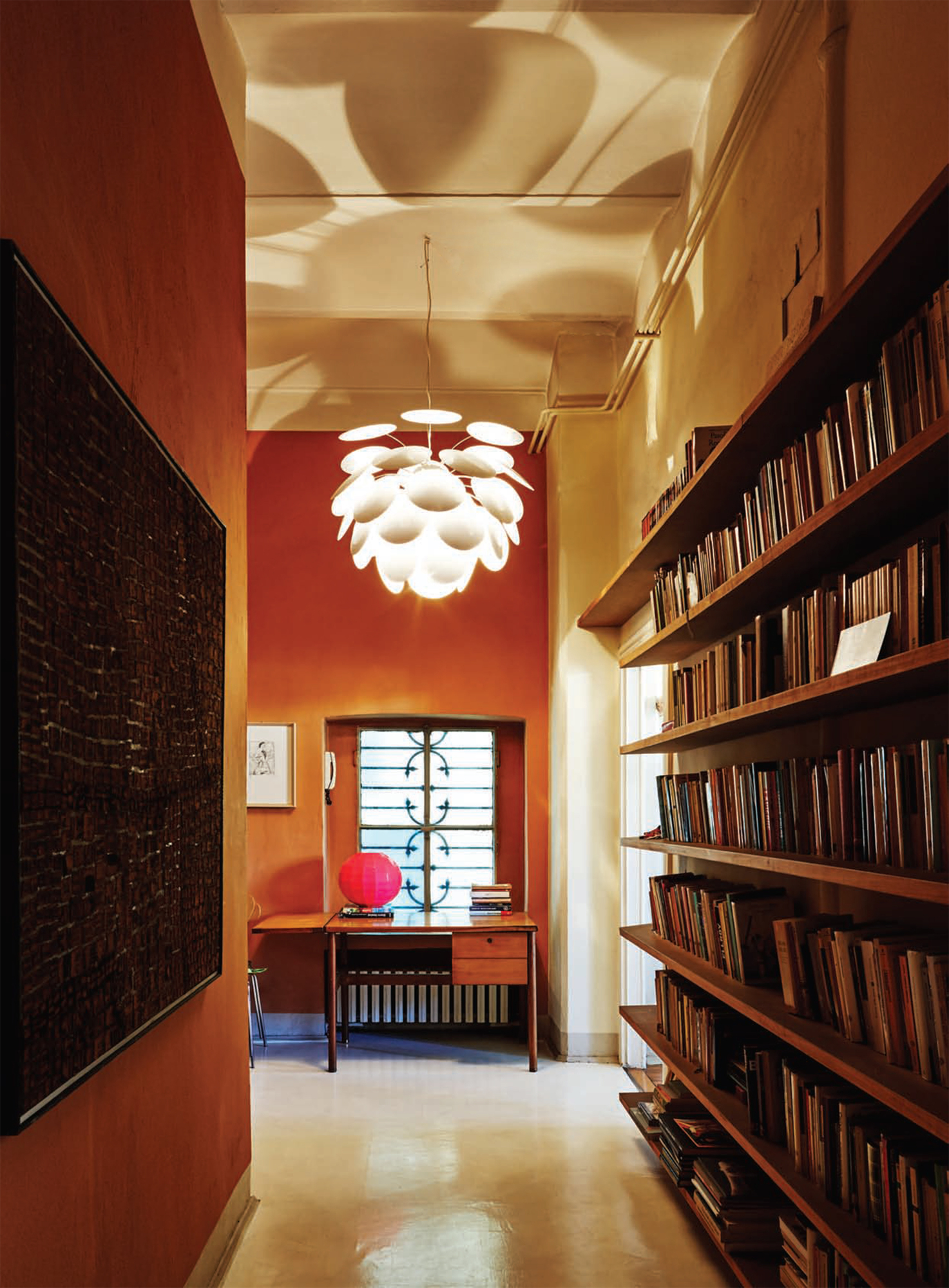 Discocó 53 LED Pendelleuchte von Marset, beige, in einem Flur mit Bücherregalen.