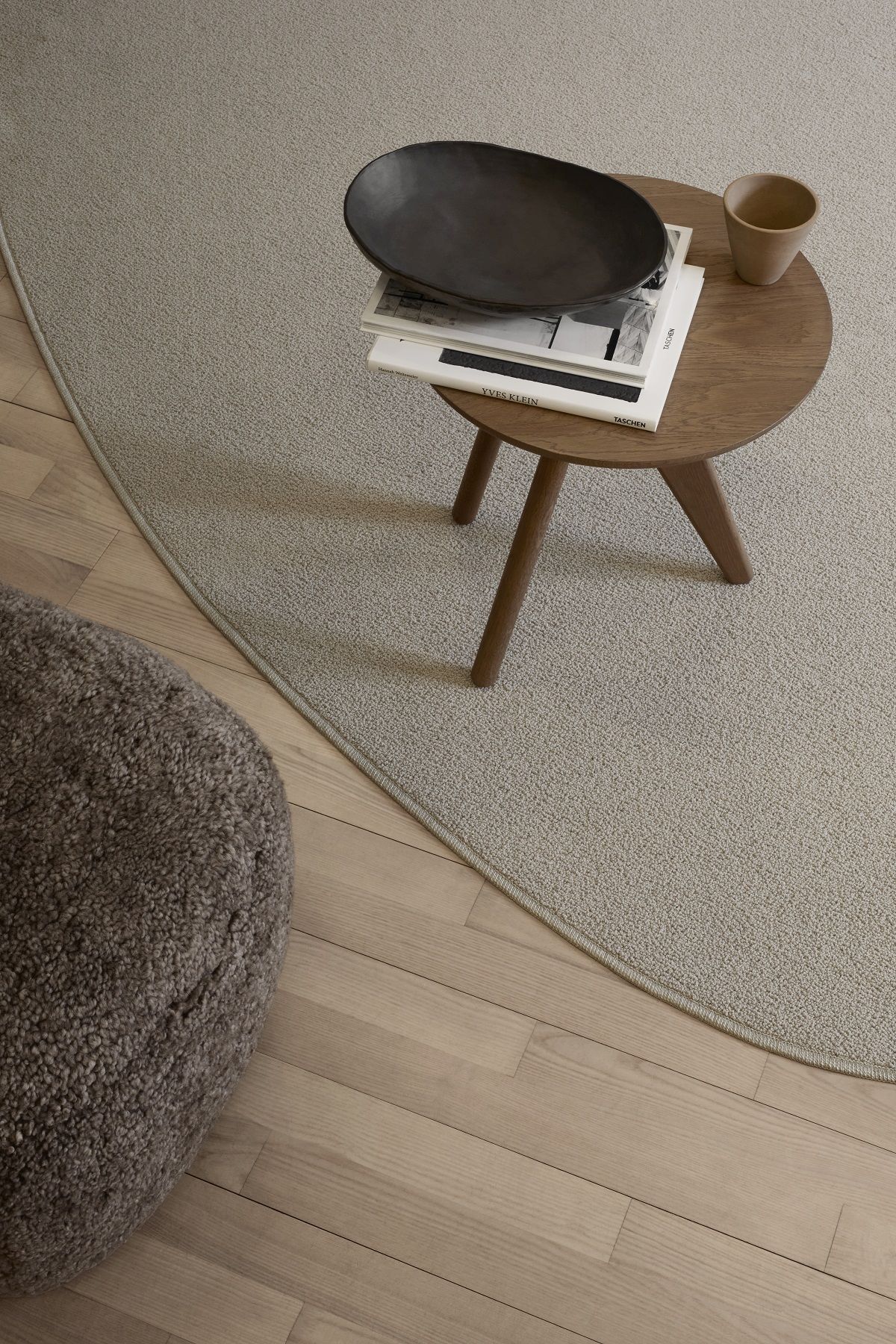 Detailaufnahme: Brauner Little Big Pouf Hocker von NORR11 neben Teppich und Beistelltisch.