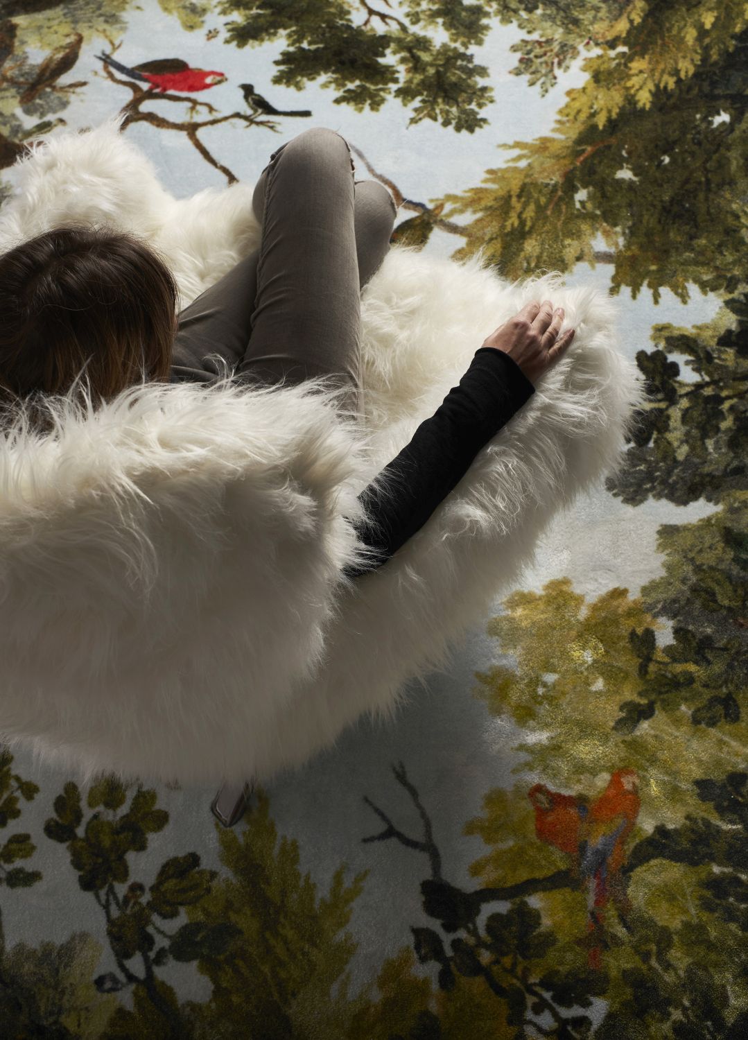 Frau entspannt im Guelfo Sessel mit Fellbezug von Opinion Ciatti auf gemustertem Teppich.