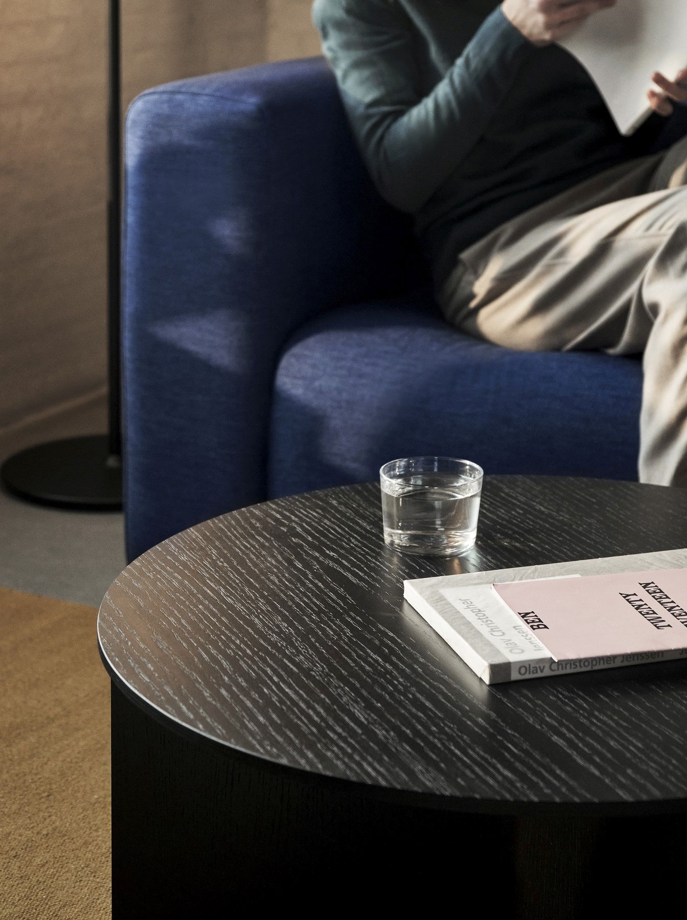 Nahaufnahme des Hay Slit Table Wood Round Beistelltisches aus Holz mit Buch und Wasserglas.