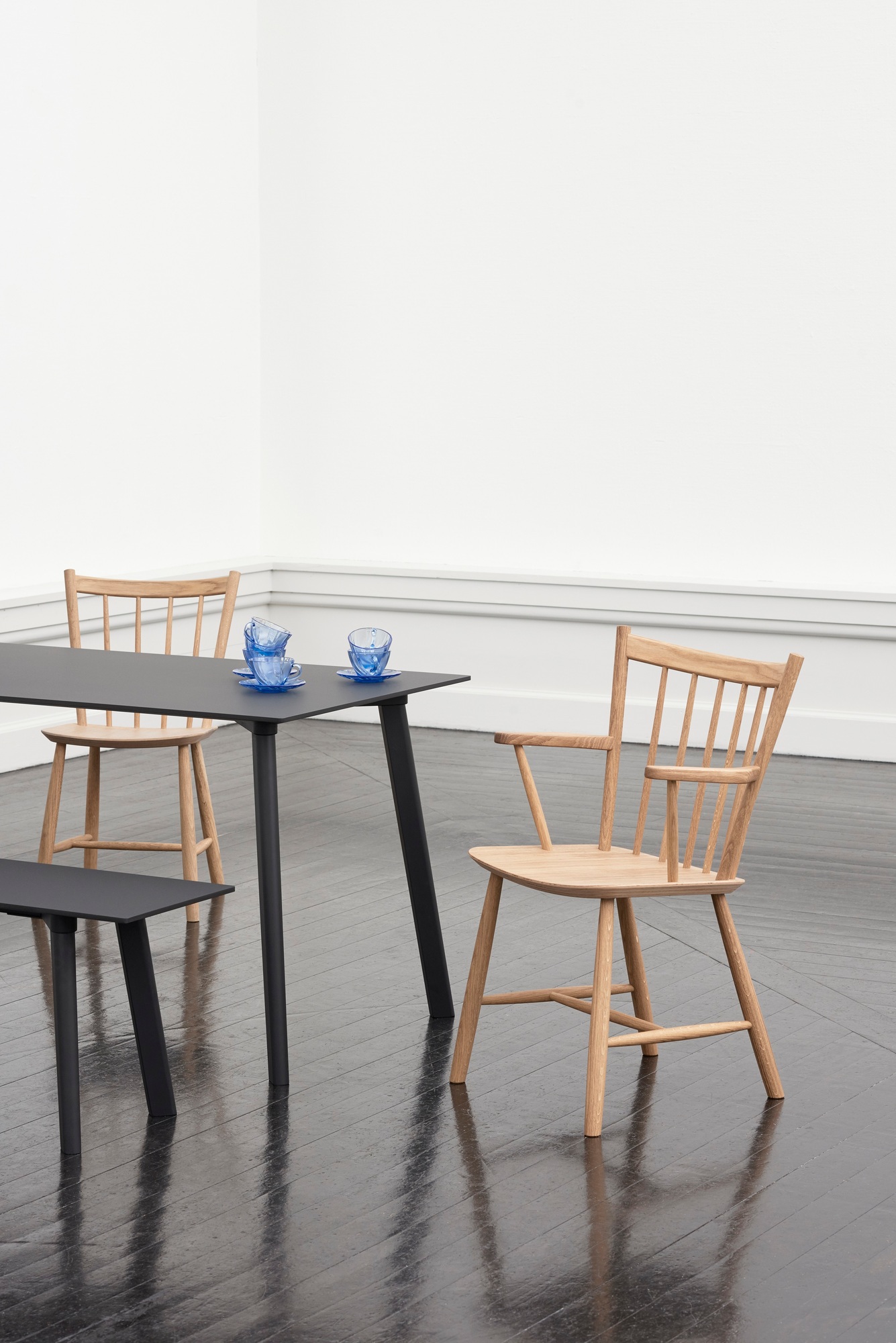 Heller J42 Stuhl von Hay aus Holz mit Armlehnen an einem Esstisch.