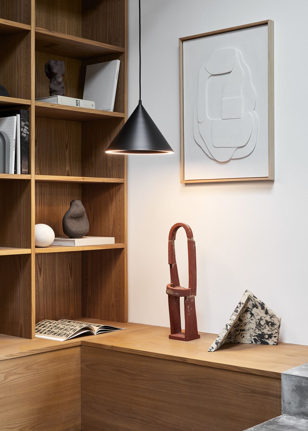 Annular Pendelleuchte L Woud Schwarz über einem Regal, moderne Hängeleuchte für stilvolle Innenraumbeleuchtung.