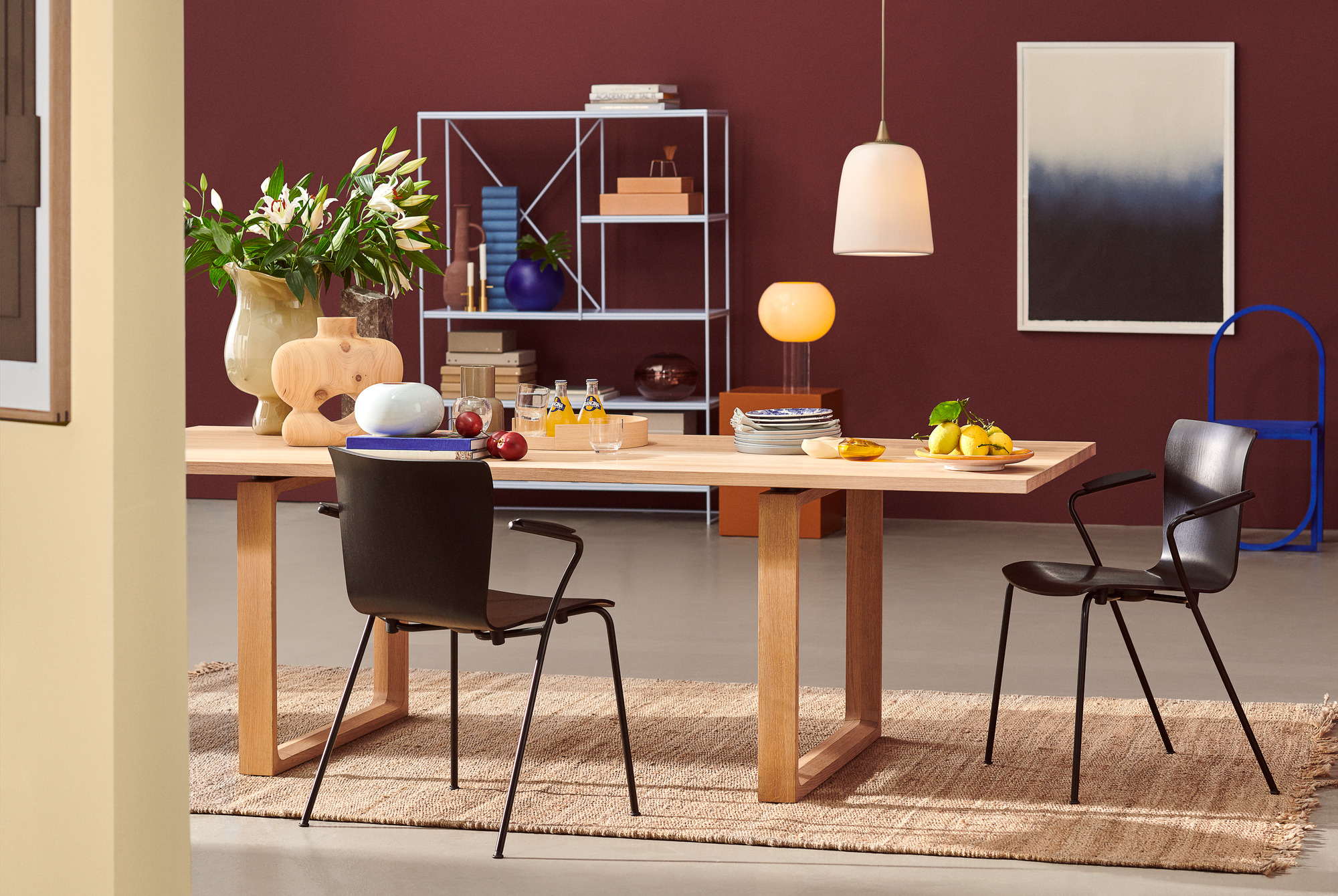 Esszimmer mit Holztisch, Teppich und zwei schwarzen Vico Stühlen von Fritz Hansen.