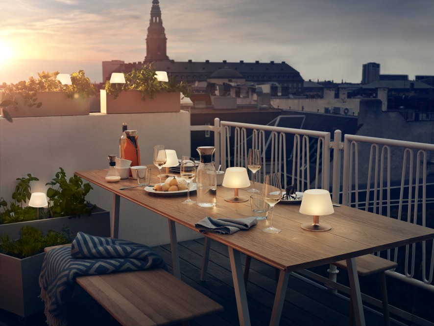 Tischszene mit Eva Solo Sunlight Tischleuchten, die warmes Licht auf einer Dachterrasse spenden.