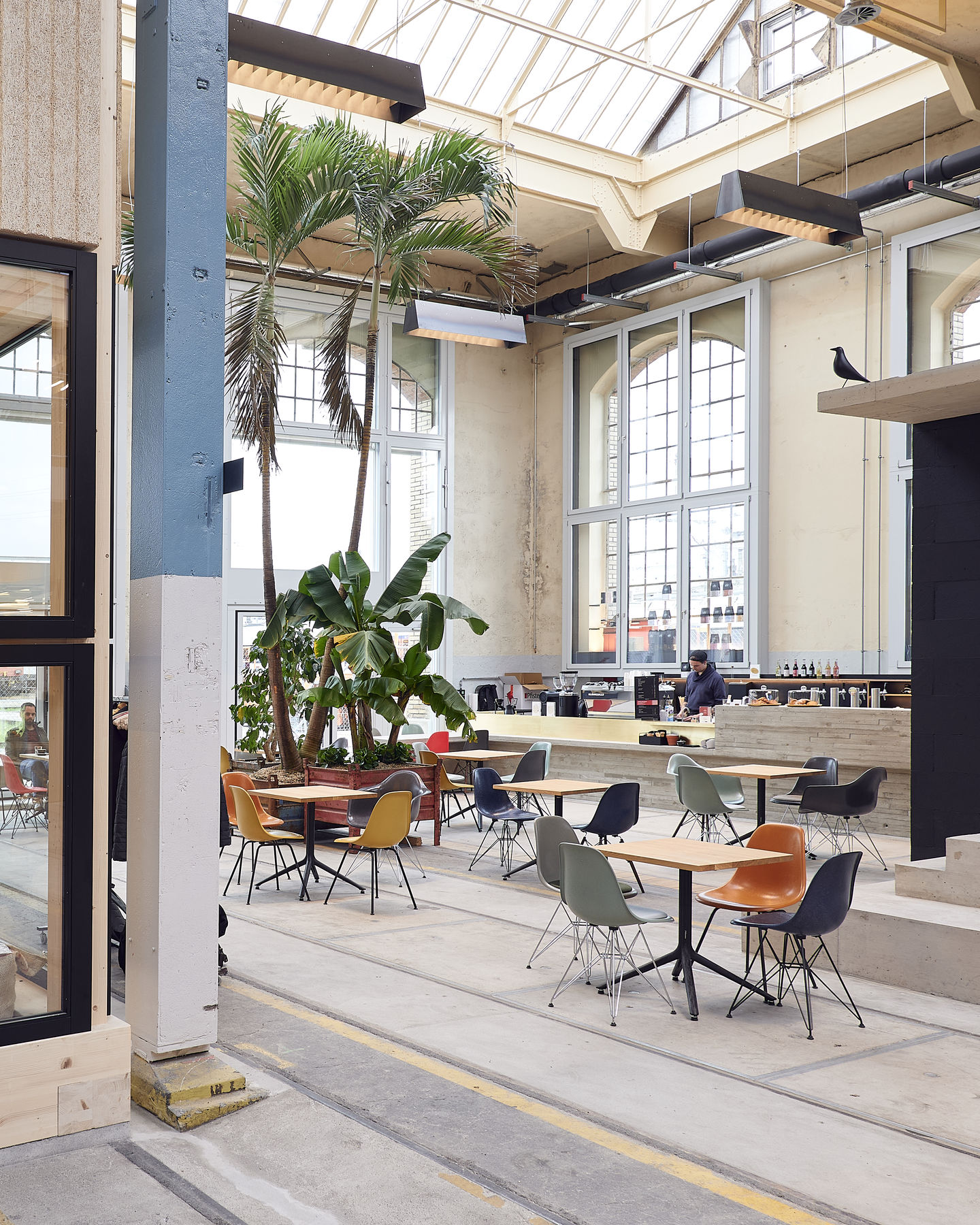 Innenaufnahme mit mehreren Eames Plastic Side Chairs von Vitra an Tischen in einem Café.