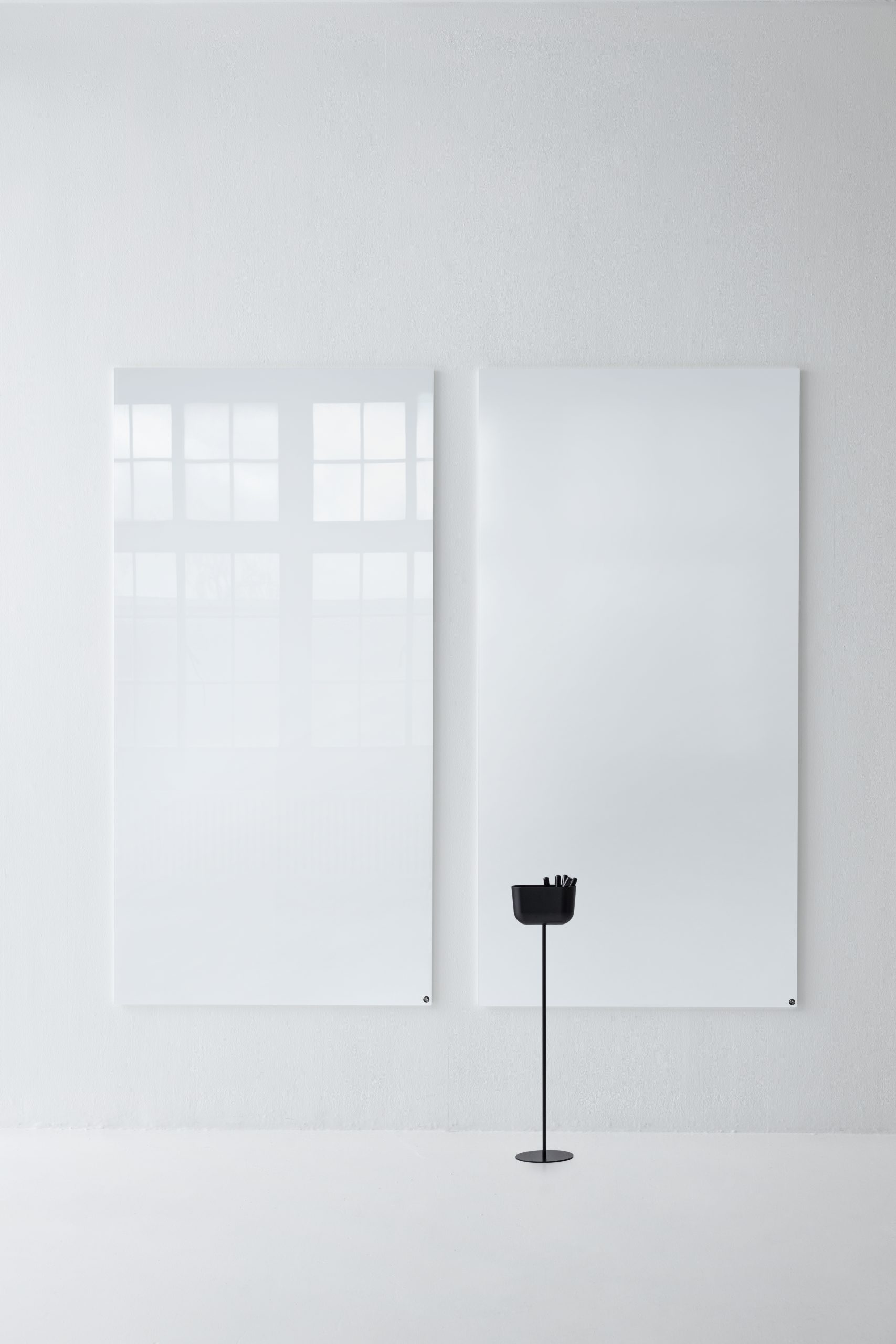 Zwei weiße, magnetische Chat Board Glastafeln an einer weißen Wand mit Stifthalter.