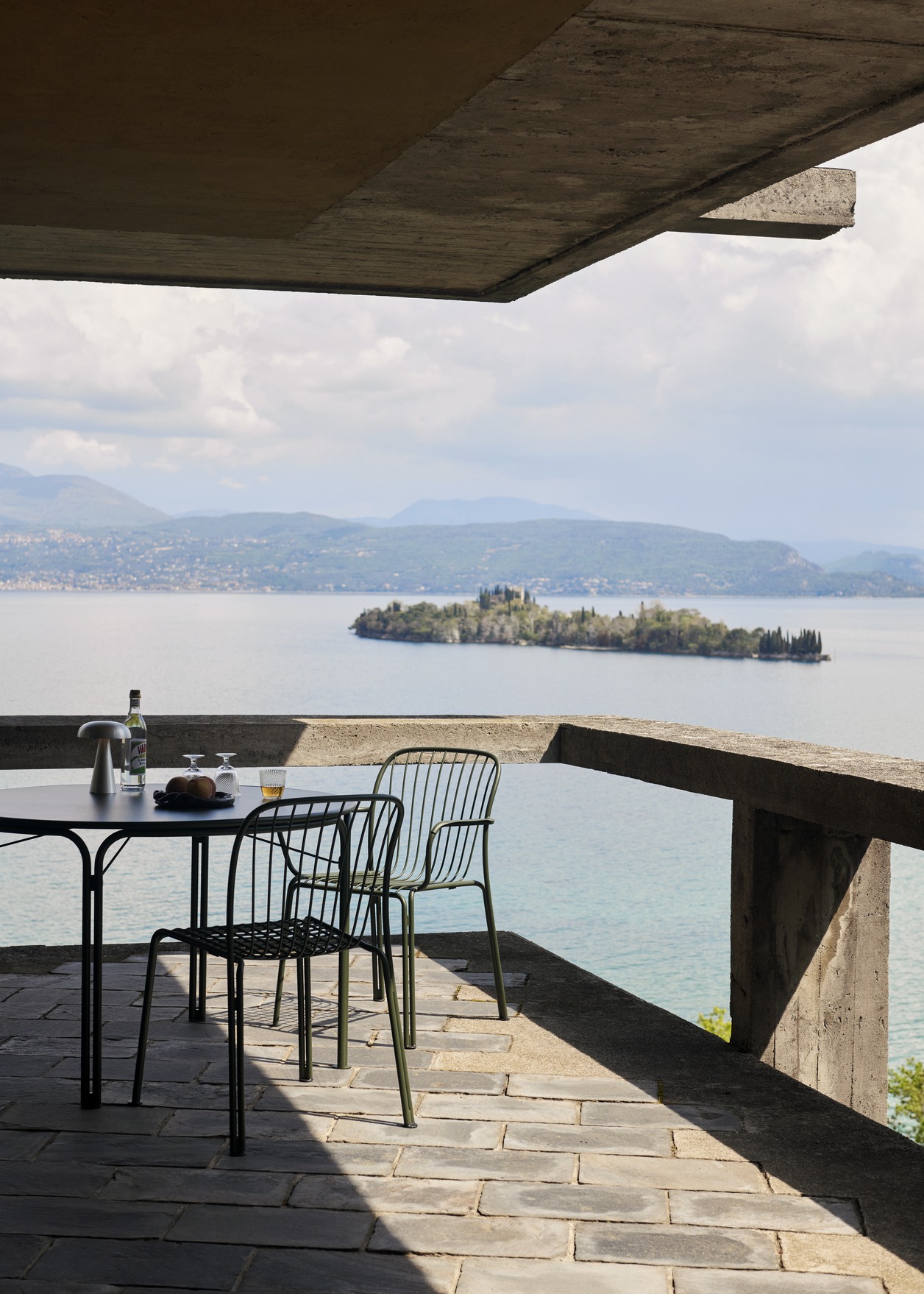 AndTradition Thorvald Stühle auf einer Terrasse mit Meerblick für ein entspanntes Outdoor-Dinner.