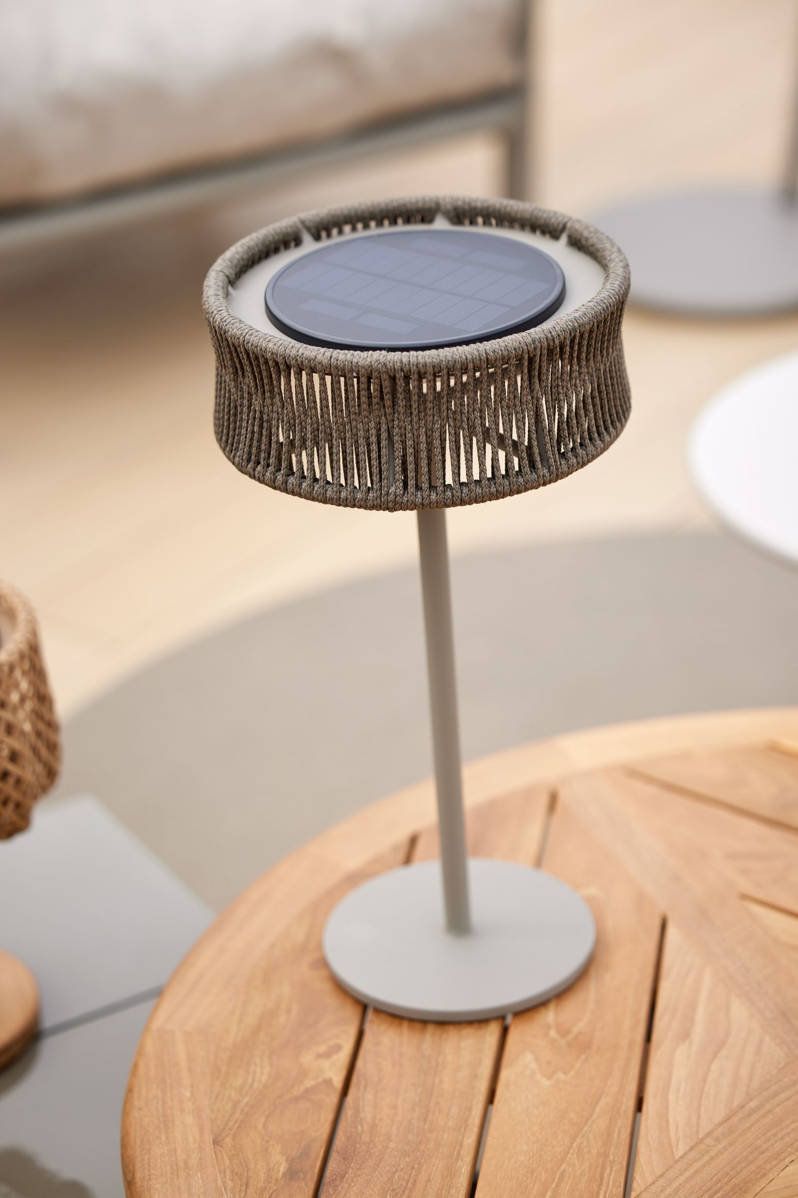 Cane-Line Illusion Outdoor Tischleuchte in Lavagrau mit Solarpanel auf einem Holztisch.