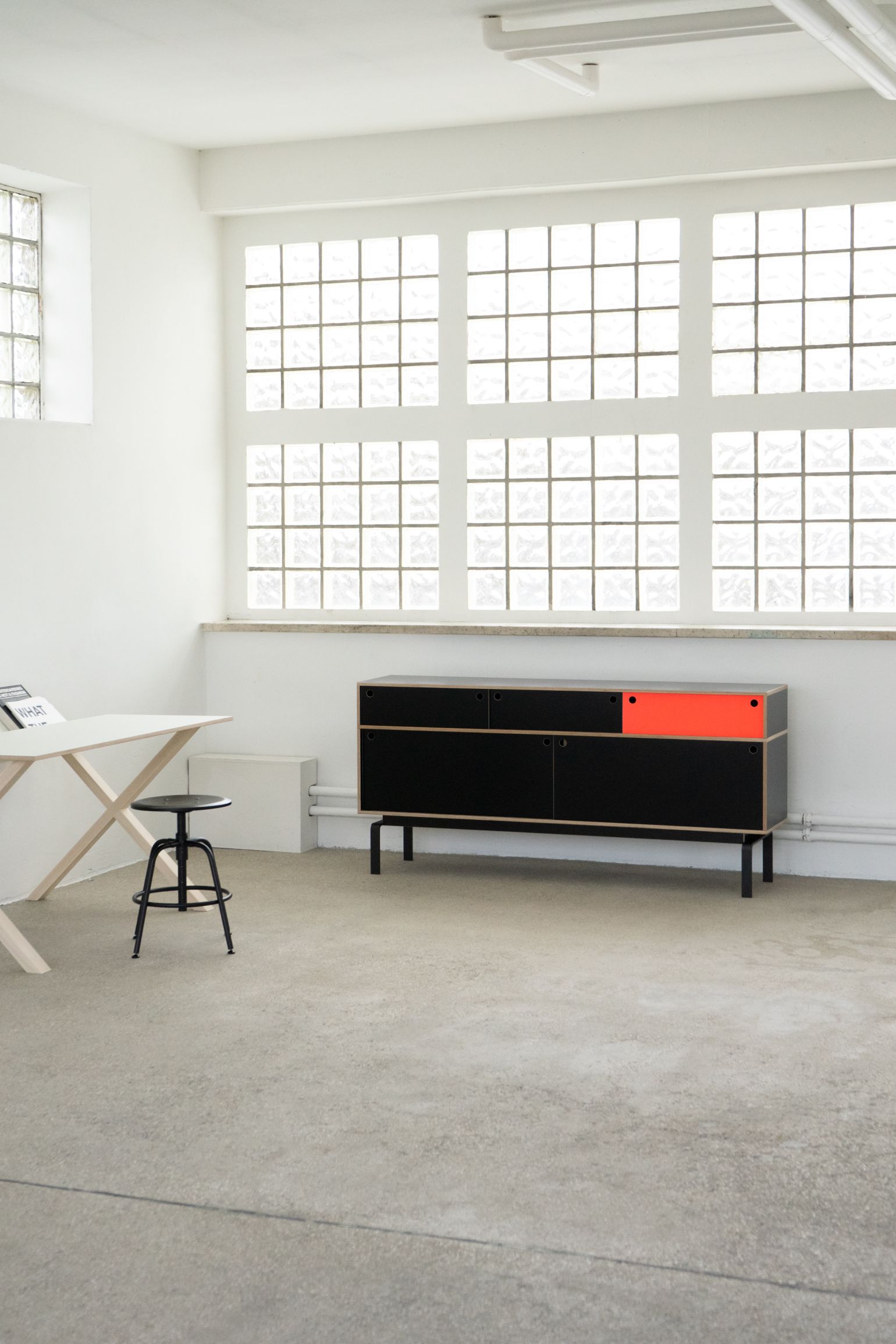 Egal Sideboard von Nils Holger Moormann, schwarz mit rotem Element, im minimalistischen Raum.