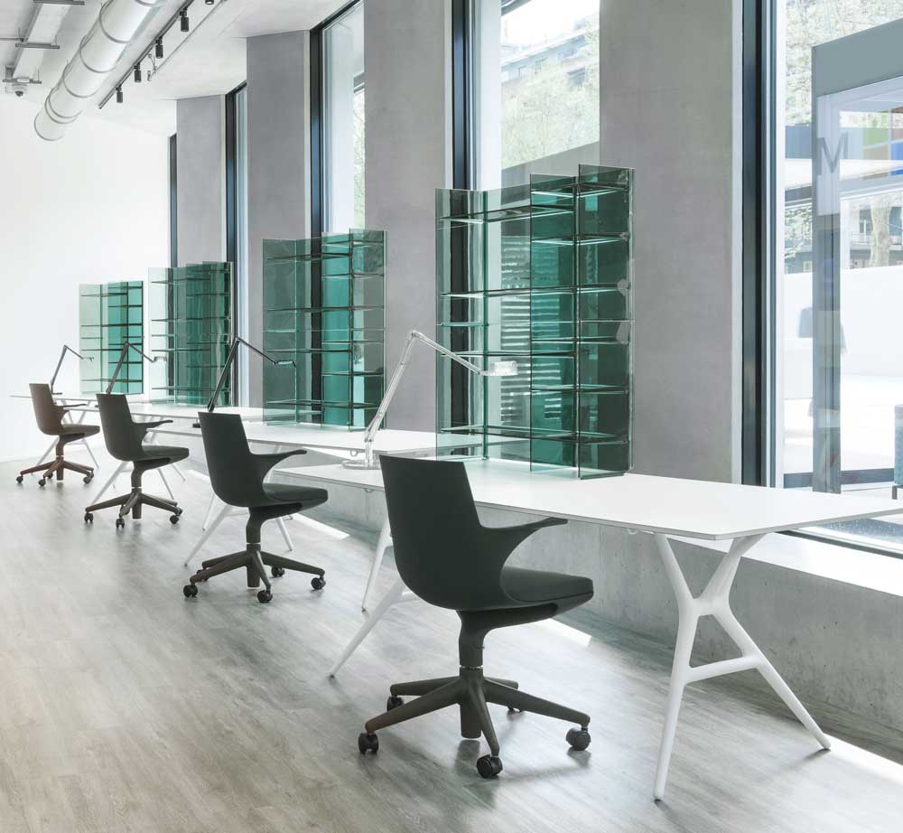Reihe von Kartell Bürotischen, Modell Spoon Table, mit Bürostühlen und Raumteilern in modernem Büro.