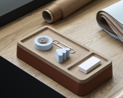 Brauner Schreibtisch-Organizer aus Kork mit Klebeband, Büroklammer, Radiergummi und Notizzettel für Bürobedarf auf einem Holztisch.