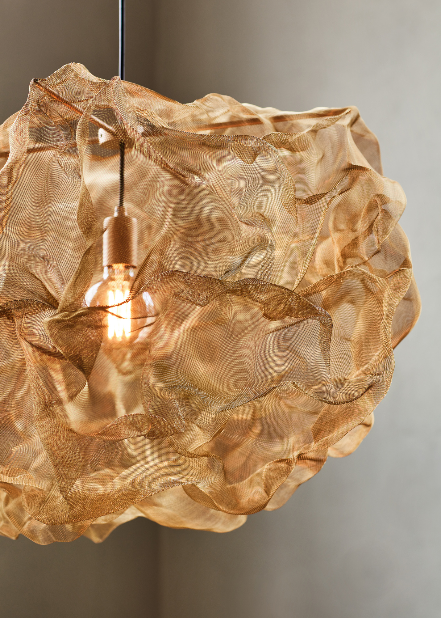 Nahaufnahme der Northern Heat Pendelleuchte mit goldfarbenem, gewebtem Lampenschirm und warmem Licht.