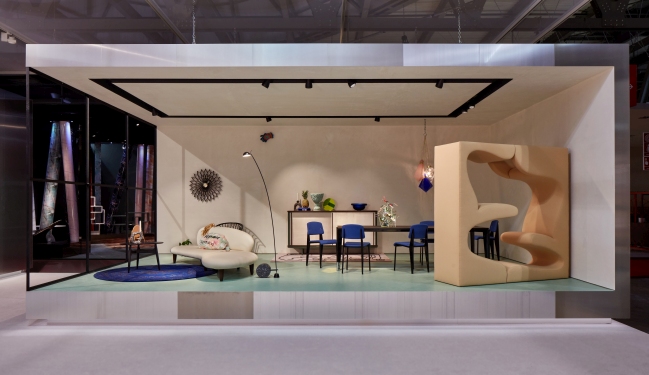 Ausstellungsraum mit Vitra Freeform Ottoman, Sofa, Esstisch und ungewöhnlichem Sessel in Beige. Modernes Möbeldesign.