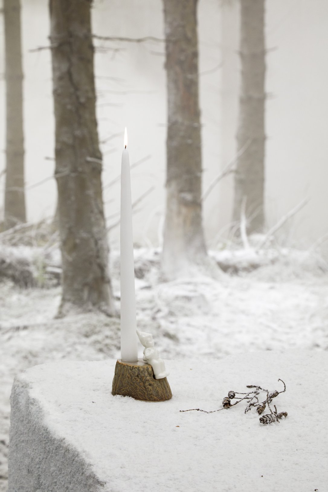 Kähler Christmas Tales Kerzenhalter mit brennender Kerze vor verschneitem Wald. Weihnachtliche Dekoration.