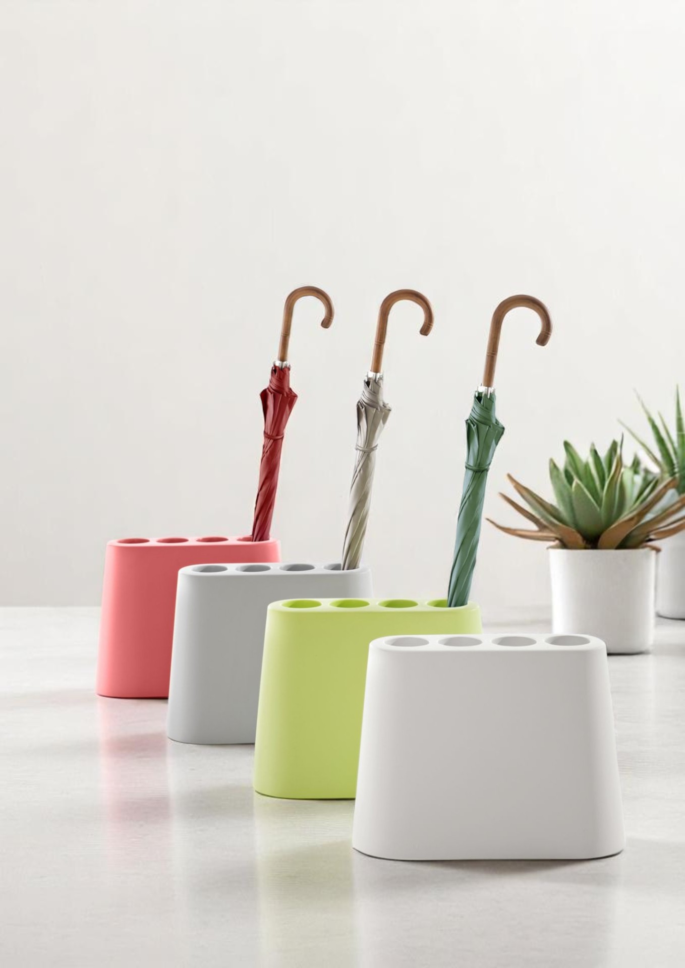 Farbenfrohe Regenschirmständer aus Keramik mit Regenschirmen in Rosa, Grau, Grün und Weiß. Moderner Schirmständer für Zuhause.