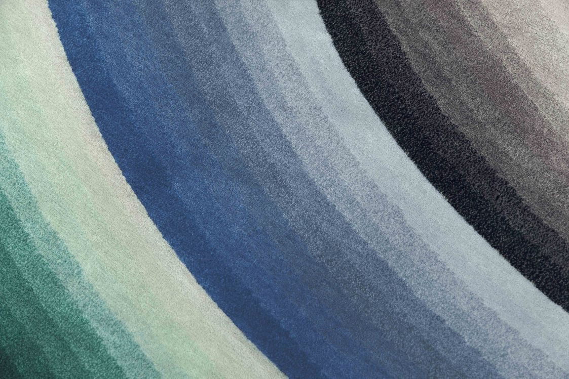 Detailaufnahme des blauen Mirage Teppichs von Gan mit Farbverlauf von Grün bis Grau.