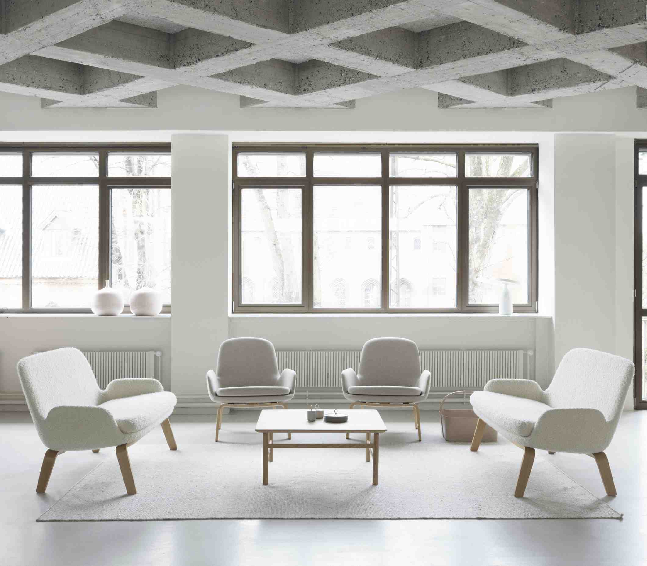 Helles Wohnzimmer mit Grow Table Couchtisch von Normann Copenhagen und Sesseln auf einem Teppich.