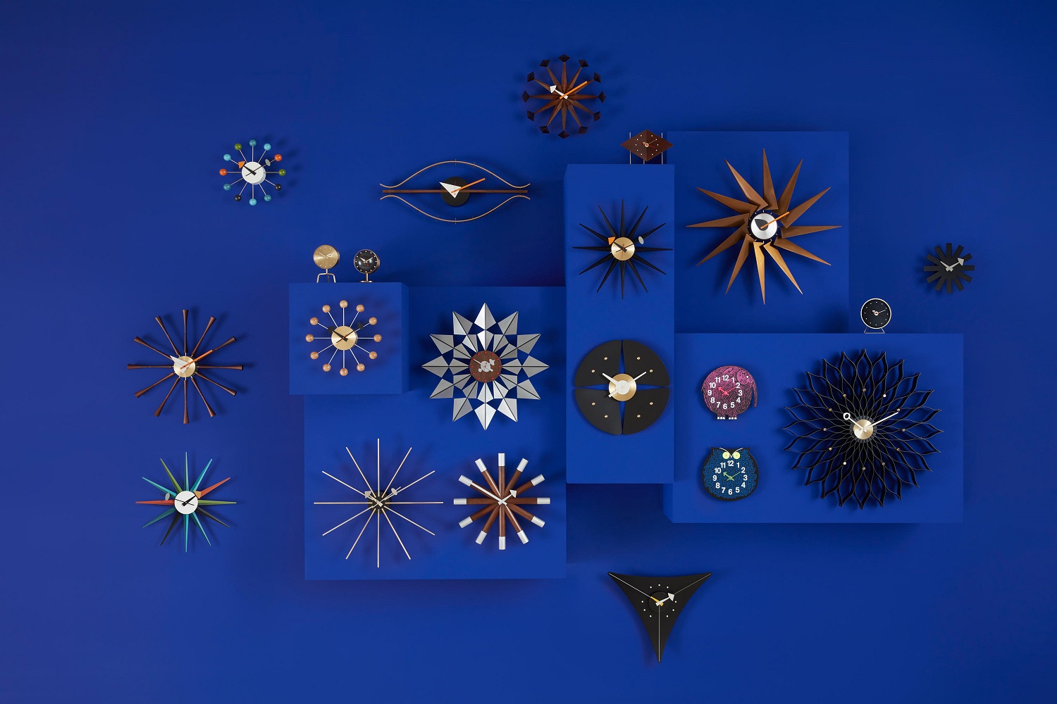 Vielfalt an Vitra Wanduhren, darunter die Nelson Flock of Butterflies Uhr, auf blauem Hintergrund.