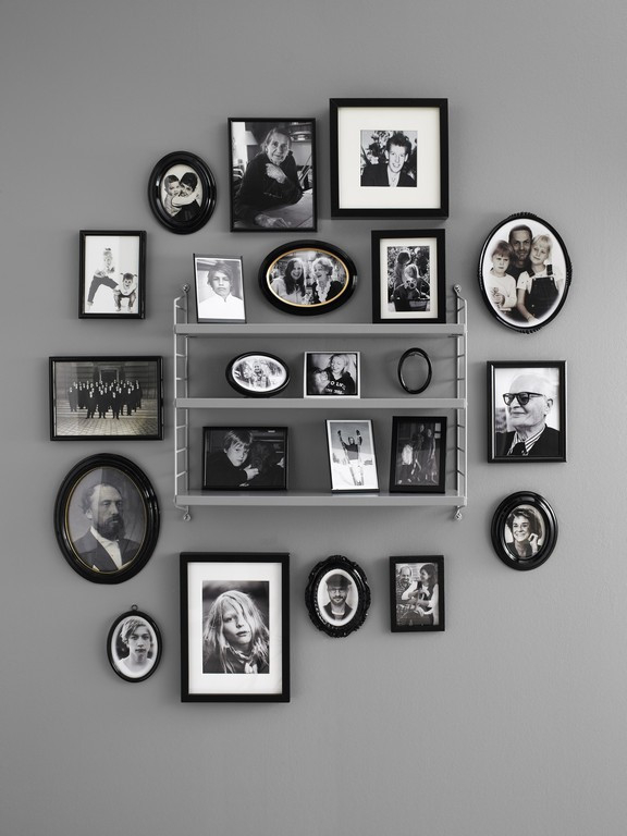 Graues String Pocket Regal von String Furniture an einer Wand mit vielen Schwarzweiß-Fotografien.